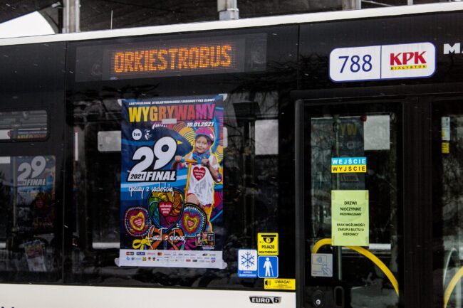 zdjęcie przedstawia plakat Wielkiej Orkiestry Świątecznej Pomocy wywieszony w miejskim autobusie