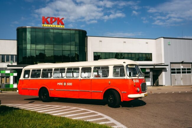 zdjęcie przedstawia czerwony autobus na parkingu kpk